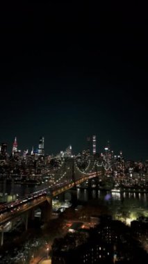 Queens ve Manhattan 'ın gece aydınlık siluetinin dikey videosu, Queensboro Köprüsü ve Doğu Nehri havadan görülebiliyor..