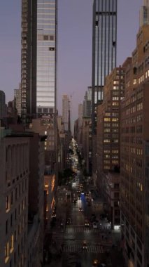 Manhattan, New York 'ta, şehir merkezinde, sari taksi ve arabalarin, alacakaranlıkta uzun binalarla çevrili bir caddede dolastigi düşey bir video var..