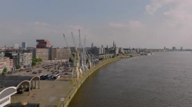 Kamera Antwerp ufuk çizgisini, iskele vinçlerini ve Scheldt Nehri 'ni gösteriyor. Bazı turistler ve yerliler güneşli yaz gününün tadını çıkarıyorlar..