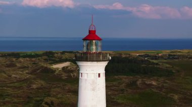 Lyngvig Fyr deniz feneri, kendine özgü kırmızı tepesi ile Danimarka 'daki Ringkobing Fjord manzarasına bakan bir tepenin üzerinde duruyor..