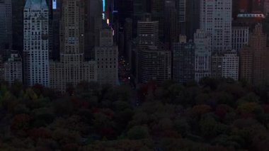 Central Park 'ın 57. caddesindeki vitrinlere bakan kamera, Manhattan' ın göbeğindeki yüksek binaları çarpıcı bir günbatımına karşı aydınlatıyor, canlı bir şehir manzarası yaratıyor..