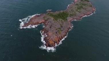Havadan bakıldığında, Finlandiya 'da kırmızı granit kayalıkların derin mavi Baltık Denizi ile buluştuğu küçük bir ada sergilenmektedir..