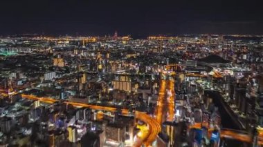 Geceleri büyük şehrin hava panoramik hipersüratli görüntüleri. Aydınlanmış caddelerin ve binaların üzerinden uç. Osaka, Japonya.