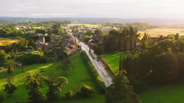 Orta Avrupa 'da içinden yol geçen bir köyün havadan görünüşü. Güneş batıyor, evler ve tarlalar boyunca uzun gölgeler bırakıyor..