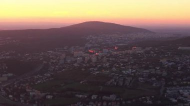 Slovakya 'nın Bratislava şehrinde güzel bir turuncu gün batımında kameralar görülüyor. Devinska Kobyla dağı arka planda görünür..