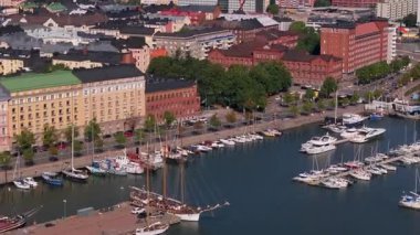 Helsinki, Finlandiya 'nın deniz manzarası yelkenli ve yatlı limana odaklanıyor. Rıhtımdaki mimari ve işletmeleri gösteren kameralar sağa doğru dönüyor..