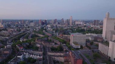 Rotterdam 'ın günbatımında şehir manzarası yollar, yerleşim yerlerindeki binalar ve modern şehir silueti ön plana çıkıyor..