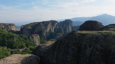 Yunanistan 'ın Meteora kentindeki büyüleyici kaya oluşumlarında, yukarıda tünemiş bir manastırla baş döndürücü uçurumlar yer alıyor. Manzara manzaraları doğal güzellik ve ruhani huzuru harmanlıyor..