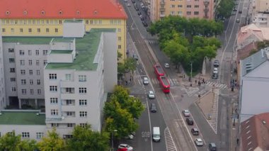 Çek Cumhuriyeti, Brno 'da bir kavşaktan geçen kırmızı bir tramvayın hava görüntüsü. Şehir manzarasında arabalar ve yayalar geziniyor..