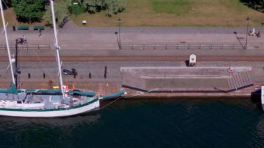 Güneşli bir yaz gününde Stockholm Limanı 'na yanaşan yelkenlilerin hava görüntüsü. Gezginler canlı yeşil alanlardan geçerek limanın tadını çıkarıyorlar..