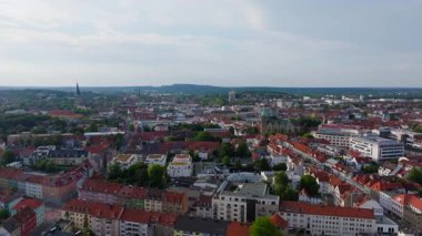 Osnabruck şehir merkezinde büyüleyici çatılar sergileniyor, St. Marys kilise kulesinin yer aldığı, bereketli yeşil tepeler tarafından çerçevelenmiş, parlak bir yaz gökyüzü altında, çarpıcı bir şehir manzarası yaratıyor..