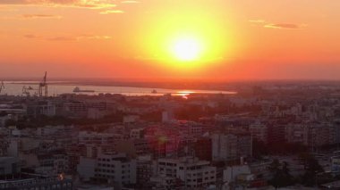 Günbatımı Yunanistan 'ın Selanik kentini sıcak turuncu bir tonla kaplıyor. Titreyen gökyüzü sakin Ege Denizi 'nden yansıyarak kentsel mimari ve sakin suların çarpıcı bir karışımını sergiliyor..