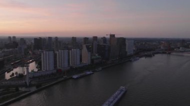 Gün batımında nefes kesen Rotterdam silueti, akşam ışığında parlayan gökdelenler ve aşağıda akan sakin nehirler..
