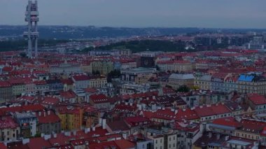 Hava görüntülerinde Prag çatıları güneş batarken gösteriliyor, şehri altın sarısı bir renkle kaplıyor. Zizkov Televizyon Kulesi alacakaranlıkta belirgin bir şekilde yükseliyor.