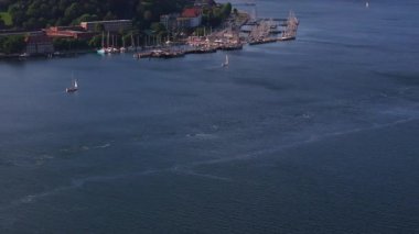 Hava görüntüleri, Almanya 'nın Kiel kentinde çeşitli boyutlarda teknelerle dolu bir marinayı yakalıyor. Yelkenliler, canlı deniz atmosferini vurgulayarak limana doğru süzülür..