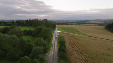 Belçika 'da manzaralı bir kırsal yolda giden arabaları hava görüntüsü yakalıyor. Yeşiller ve ağaçlar kırsal alanların cazibesini arttırır..