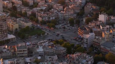 Hava görüntüleri Selanik şehir merkezini gün batımında trafik yoğunluğuyla yakalıyor. Kalabalık caddelerde hareketli binalar ve şehir mimarisi ile çevrili arabalar dokuyor..
