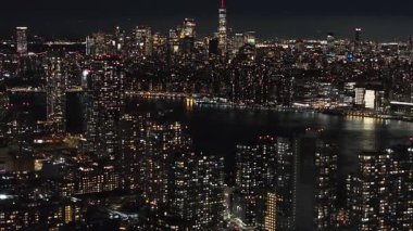 Aşağı Manhattan ve Doğu Nehri 'nin geceleri hava manzarası. Kamera New York gökdelenleri üzerinde hareket ediyor. Şehir ışıklarının çarpıcı manzarasını sunuyor..