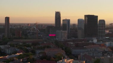 Sıcak güneş ışığı Bratislavas modern şehir manzarasını yıkıyor. Gökyüzü gündüzden geceye geçerken. İkonik Apollo Köprüsü renkli ufukta beliriyor. Bratislava, Slovakya 5 Temmuz 2024