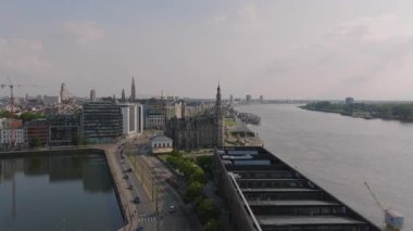 Antwerps 'in canlı şehir manzarası Loodswezen, Scheldt nehri, arabalar yollar boyunca ilerliyor ve yayalar canlı bir şehir atmosferinin tadını çıkarıyorlar..