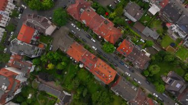 Kamera caddelerin yukarısında ve Munster, Almanya 'nın kırmızı çatılarında ilerliyor. Arabalar aşağıda park halinde ve bir oyun alanı görünüyor..