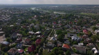 Sakin nehir, Litvanya 'nın Kaunas kentindeki bir yerleşim bölgesinden akar. Yeşiller yemyeşil ağaçlar evlerin etrafını kırmızı çatılarla çevreler..