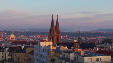 Kuşlar güneş doğarken Prag, Çek Cumhuriyeti 'nin çatılarında uçuyorlar. Vinohrady 'deki St. Ludmila Bazilikası' nın ikiz kuleleri arka planda görünür..