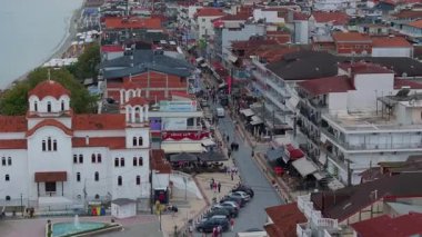 Yunanistan 'ın Paralia Katerinis limanında turistler yürüyor. Sahilde beyaz bir Doğu Ortodoks kilisesi görülebilir. Arka planda Ege Denizi var..