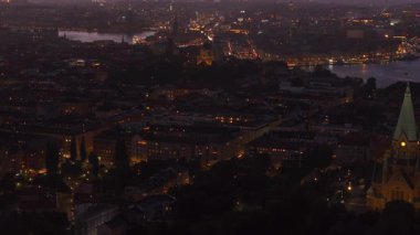Stockholm ufuk çizgisi aydınlık binalar ve gün batımında canlı araba trafiği ile parıldıyor, çarpıcı, renkli bir gökyüzü ile çerçevelenmiş, şehirlerin cazibesini ön plana çıkarıyor..