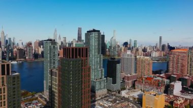 Queens 'teki modern cam ve çelik yerleşim kuleleriyle Long Island' daki East River rıhtımının havadan görüntüsü. Manhattan şehir merkezindeki ikonik gökdelenler.