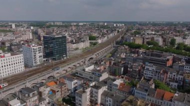 Belçika 'nın Antwerp kentindeki birçok bina ve tren yolu bulunan yoğun bir şehir manzarası. Sokakta arabalar sürüyor ve bazı bitkiler görünüyor..