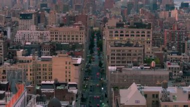 New York 'un hareketli caddeleri boyunca uçan hava manzaralı araçlar. Önde gelen binalar ve çatılar manzarayı doldurarak, akşam saatlerinde kentsel manzarayı vurguluyor.