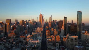 Sıcak güneş ışığı Manhattan şehir merkezindeki New York Citys gökdelenlerini, Empire State Binası da dahil olmak üzere kaplamaktadır. Gün batımında, nefes kesen bir şehir sahnesinde güneş ufuktan batar..