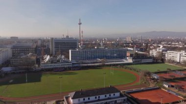Frankfurt şehir manzarası, üniversite spor kompleksinin üzerinde yükselen Europaturm telekomünikasyon kulesini gözler önüne seriyor, koşu pisti, tenis kortu, ragbi sahası.