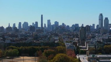 Brooklyn kentindeki bir ağaç parkının havadan görünüşü. Apartman binaları, işyerleri, yayalar ve müşteriler ile dolu caddelerde arabalar sürüyor..