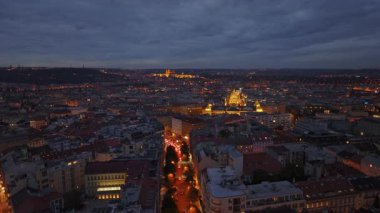 Prag şehir merkezinin hava manzarası mavi saatte aydınlanıyor. Caddelerde trafik ve arka planda Kale var..