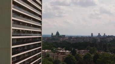 Brüksel silueti boyunca uzanan gökdelenler, apartmanlar ve canlı yeşil ağaçlar arasında kurulmuş kutsal kalbin bazilikasını gözler önüne seriyor ve canlı bir kentsel atmosfer yaratıyor..