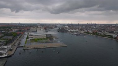 Hava görüntüleri gri bir günde Kopenhag Opera Binası 'nın bulutların altında olduğunu gösteriyor. Tekneler kanal boyunca süzülüyor, sakin şehir sahnesine canlılık katıyor..