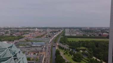 Parçalı bulutlu gökyüzünün altında ufukta uzanan binalar, parklar ve yollarla Lahey şehir manzarası.