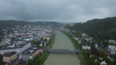 Salzach Nehri 'nin Salzburg, Avusturya' da dolaştığını gösteren hava perspektifi. Tarihi binalar ve köprüler bulutlu bir gökyüzünün altındaki şehir manzarasını dolduruyor..