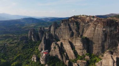 Meteora, Yunanistan 'daki inanılmaz kaya oluşumlarının hava görüntüsü. Kamera yavaş yavaş döner, eşsiz manzarayı gözler önüne serer ve kayalıkların tepesine tünemiş antik manastırlar..
