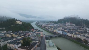 Sisin yavaşça dağıldığı Salzburg şehrinin hava manzarası. Salzach Nehri şehir merkezinden akıyor..