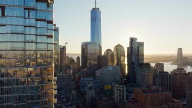 Güneş ışığı cam gökdelen yüzeyinde parıldıyor, bir dünya ticaret merkezi ve Manhattan şehir manzarasını vurguluyor altın sabah ışığında mimari dehasıyla.