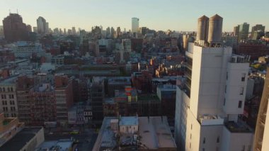 Manhattan ufuk çizgisini aydınlatan gün batımı, su kuleleri, mimari siluetler ile kentsel yoğunluğu vurgulayan dramatik bir perspektiften çatı detayları.