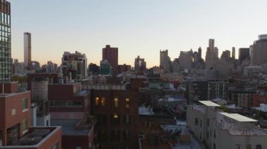 Güneş ışığı, Manhattan 'ın aşağı doğu yakasının çatılarına altın renkleri döküyor. Su kuleleri, New York' un uzak gökdelenleri arasında kentsel yoğunluğu ortaya çıkarıyor..