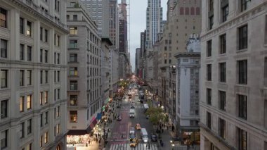 Şehir caddesi trafik dolu ve alacakaranlık sırasında yürüyen yayalar, Manhattan 'ın şehir ışıklarıyla aydınlanıyor..