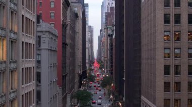 Manhattan şehir merkezinin pencerelerinin hava manzarası, alacakaranlık sırasında yüksek binaların altındaki araç hareketlerini takip etmek, şehir merkezindeki mimari ihtişamı vurgulamak..