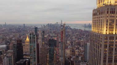 Karanlık Manhattan siluetine karşı Empire State Binası 'nı aydınlatacak sıcak bir akşam aydınlatması..