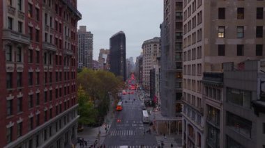 5. Cadde 'deki hareketli New York caddesi, arka planda gökdelenler ve Flatiron binaları arasında sarı okul otobüsleri sallanıyor..