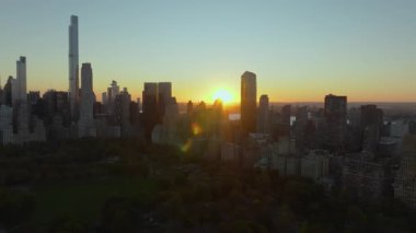 Manhattan şehir merkezindeki ikonik gökdelenlerin ardında batan güneşi görüntüleyen hava görüntülerinde Central Parks ön planda yemyeşil yeşillikler yer alıyor. Akşam ışığı New York 'u yıkıyor..